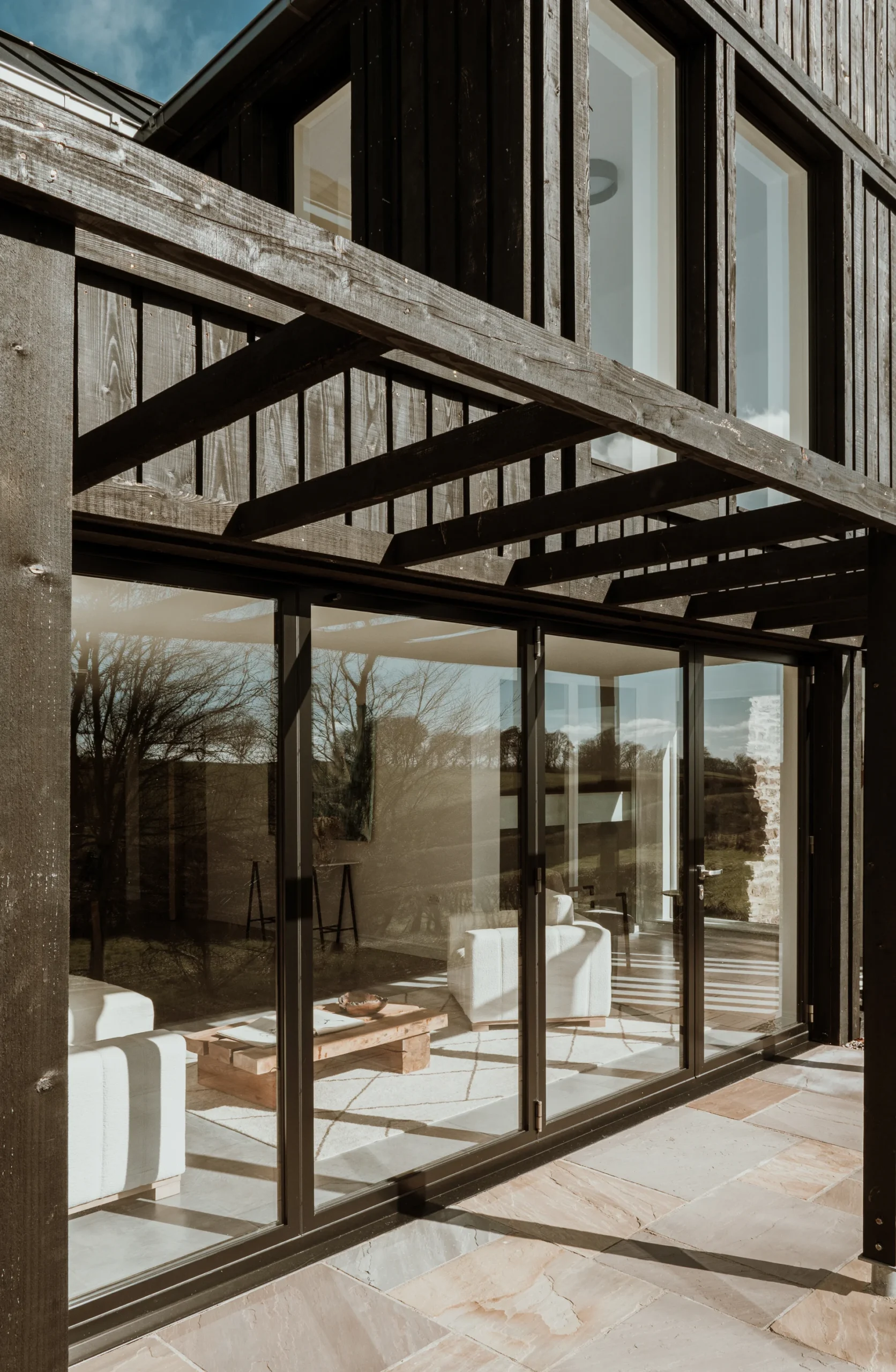 Modern timber pergola over sliding glass doors, connecting indoor and outdoor spaces in a sustainably designed home.