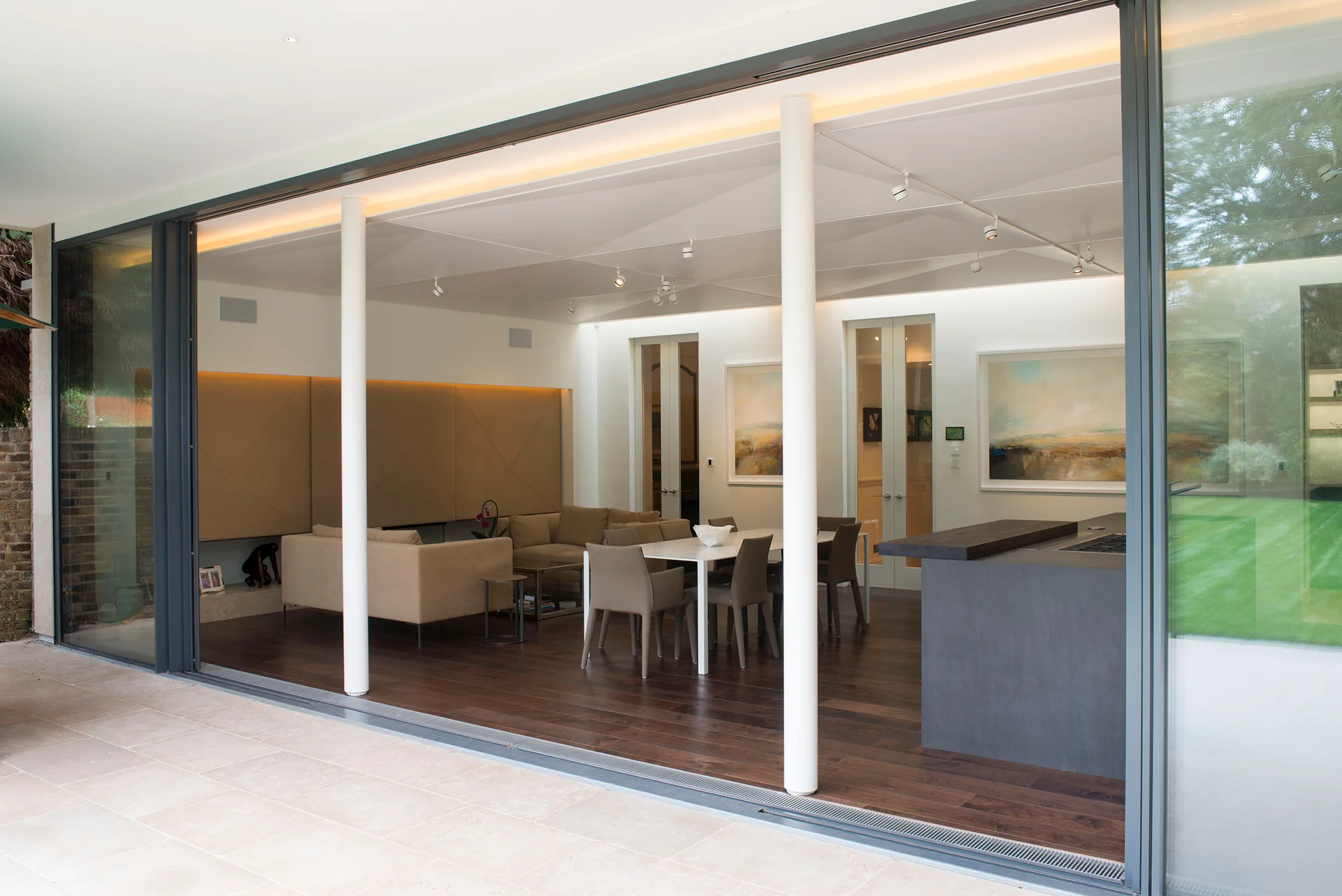 Spacious open-plan living area with large sliding glass doors, modern furniture, and wooden flooring.