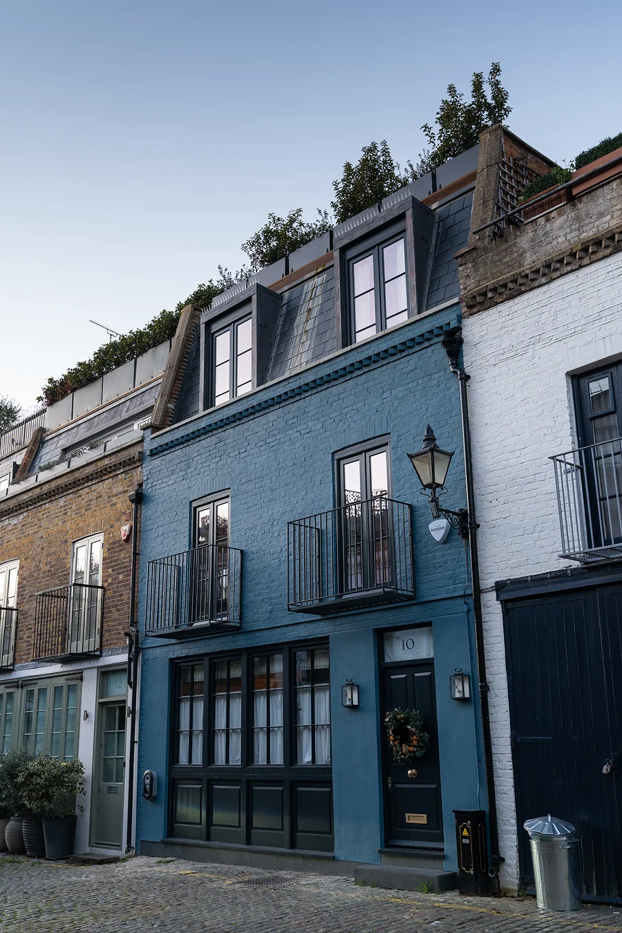 Painted blue mews house with black-framed windows, Juliet balconies, and a festive wreath on the front door.