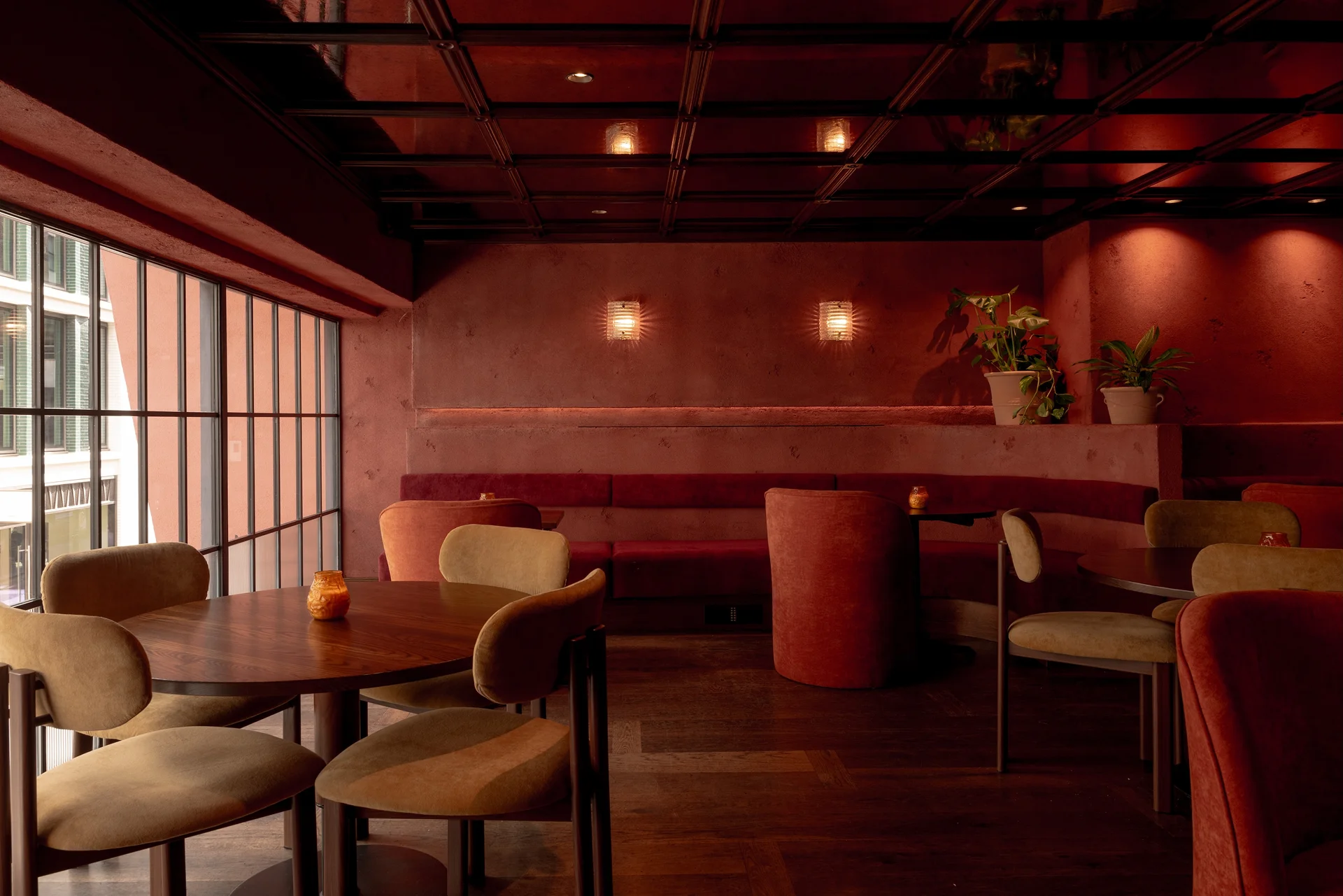 Cozy interior of a Soho restaurant featuring warm red tones, modern furniture, and soft lighting.